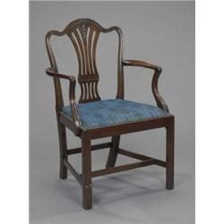 A mahogany elbow chair, in Hepplewhite style, the arched back and pierced waisted splat carved wi...
