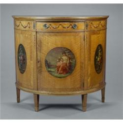 A late 19th century painted satinwood Adam revival semi-elliptical side cabinet, painted with a c...