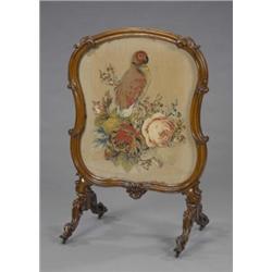 An early Victorian rococo revival firescreen, of leaf carved scrolling cartouche form, enclosing...