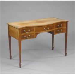 An Edwardian mahogany serpentine kneehole dressing or writing table, fitted five shallow drawers...