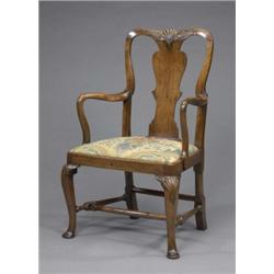 A George II walnut elbow chair, the curved hoop back carved with shell and acanthus scrolls above...