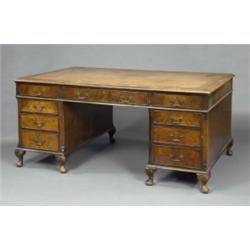 A large walnut partners desk, in George II style, the ovolo moulded rectangular top with crossban...