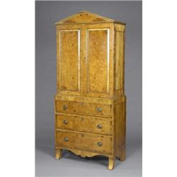 A satin birch and burr walnut cabinet-on-chest, enclosed by a pair of doors with raised and field...