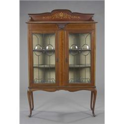 An Edwardian mahogany Sheraton revival display cabinet, enclosed by a pair of leaded doors beneat...