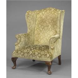 A wingback armchair, in George II style, upholstered in floral cut velvet, on mahogany cabriole l...