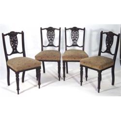 Set of four Victorian ebonized dining chairs with carved fleur de lys floral backs on turned legs wi