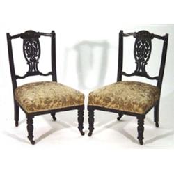 Pair of Victorian ebonized nursing chairs with carved floral backs and upholstered seats