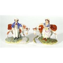 Pair of hand painted Victorian Staffordshire figures of a young boy and a girl beside cattle above a