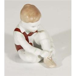 Hand painted Hungarian porcelain boy tying his shoes, marks to base, 10cm high