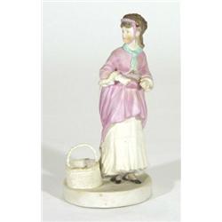 Hand painted Victorian bisque figurine of a woman in a dress beside a basket, 20cm high