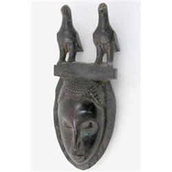 A Baule carved wood mask, Ivory Coast, with crest modelled as two birds on a plinth, 19 ins...