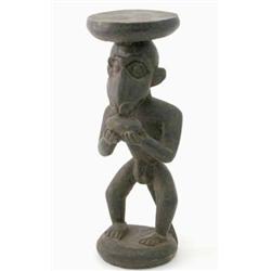 A Baule carved wood monkey god stool, Ivory Coast, modelled holding a piece of fruit, 15.75 ins...