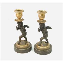 A pair of early 19th century French bronze and gilt candlesticks, on cupid figure supports with v...