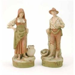A pair of Royal Dux peasant figures, male beside basket of fruit, female beside two-handled jug,...