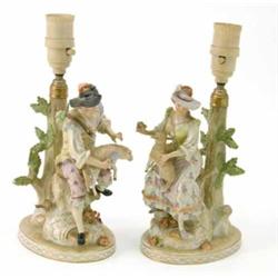 A pair of Dresden figural table lamps, one a shepherd, the other a shepherdess, each tending to a...