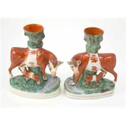 A pair of Victorian Staffordshire pottery spill vase cow groups, each cow with suckling calf bene...