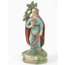 An early 19th century Staffordshire pottery figure, "St. John", robed figure holding drinking ves...