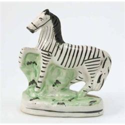A Victorian Staffordshire model of a zebra, prancing pose, on oval base, 6.25in....