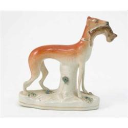 A Victorian Staffordshire pottery greyhound, holding dead hare within jaw, on oval base, 7.5in....