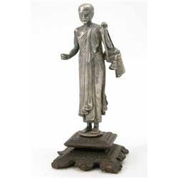 An Eastern silvered bronze figure of a Buddhist monk, 7ins, in a hardwood stand...