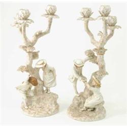 A pair of Royal Worcester candelabra, modelled with children with a frog and birds nest beside tr...