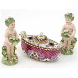 A pair of Continental porcelain figures of putti, in the style of Bow, each modelled with a flora...