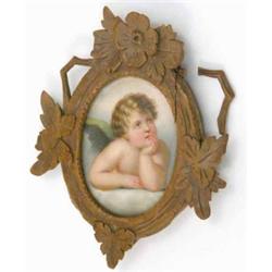 A 19th century oval porcelain plaque, painted with a cherub, in carved frame with rosette crestin...