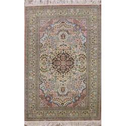 A modern Persian silk ivory ground rug, woven central circular blue medallion within a field of s...