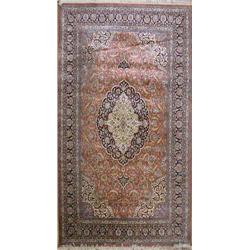 A Kashmiri Kashan style cotton and silk red small carpet, with oval ivory and dark blue medallion...
