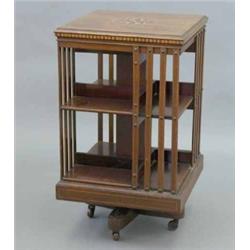 An Edwardian mahogany revolving bookcase, inlaid with ivory sea creatures and boxwood harebells,...