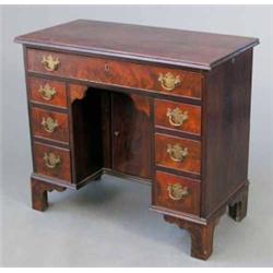 A George III design mahogany kneehole desk, with recessed cupboard and nine drawers on bracket fe...