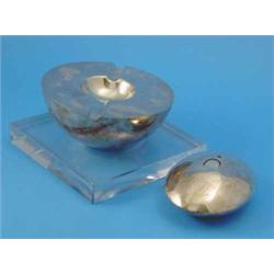 A Gucci white metal circular ashtray, with clear glass plinth base and a Gucci table lighter of o...