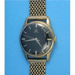 A gentleman's 9ct gold Omega wrist watch with black dial and flexible bracelet....