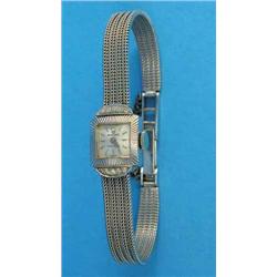 A lady's 18k white gold Rolex wrist watch with square dial and diamond set lugs, on a textured br...