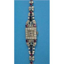 A 1940's diamond, ruby and sapphire cocktail watch with square Arabic dial and butterfly link bra...