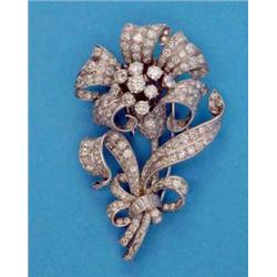 An important all diamond floral spray brooch, designed as a ribbon tied flowerhead and foliage, t...