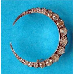 A late Victorian gold and silver round crescent moon brooch, set with a graduated row of 21 diamo...