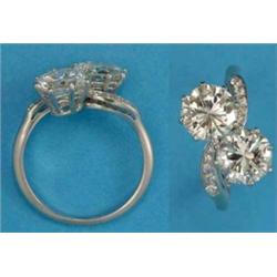 A 2-stone diamond cross over ring, the shoulders set small diamonds, each brilliant-cut stone app...