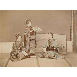 [Japan], A hand-coloured albumen print of three geisha one with fan and mask. Matted and framed...