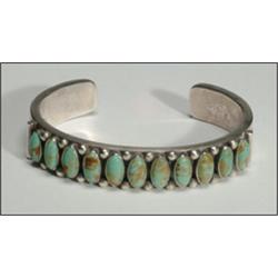 Navajo sterling silver open bangle, formed of a thick ingot band and set with a frieze of 11 ov...