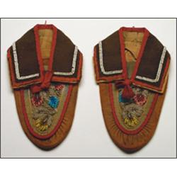 A pair of Woodland cloth and hide moccassins, decorated with floral beadwork and red trade cloth,...