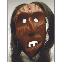 An Iroquois False Face Society mask, decorated in an all over red finish and with horse hair susp...