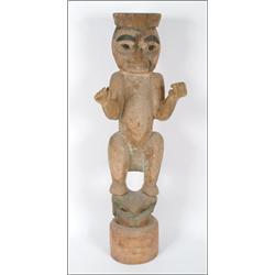 A Northwest Coast carved wood ancestor figure with extended arms, crouching on a frog, with weath...