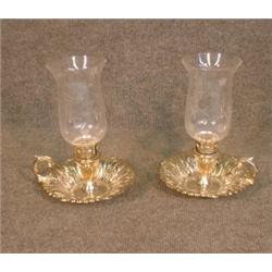 Une paire de bougeoirs à main en métal argenté munis de manchons en verre....