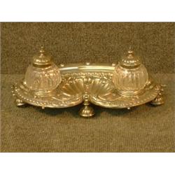 Un encrier en métal argenté à décor de coquille et de fruits....