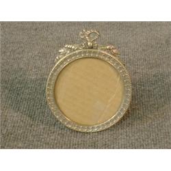 Un encadrement de photo de style Louis XVI circulaire en métal argenté....