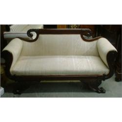 Un canapé en acajou, vers 1840, le dossier orné d'une crosse sculptée de lauriers, les accoudoirs...