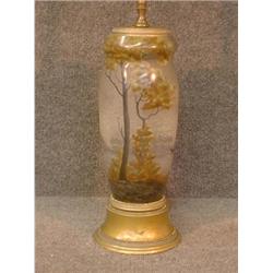 Une lampe Art Nouveau en verre à décor émaillé de paysage lacustre brun et vert sur fond gris, si...
