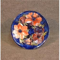 Une assiette en poterie de Moorcroft à décor fleuri sur fond bleu cobalt....