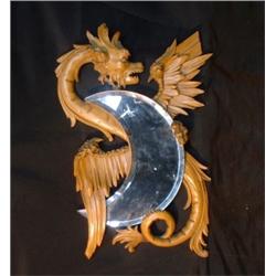 Un miroir en demi-lune sur un support en bois sculpté en forme de dragon ailé....